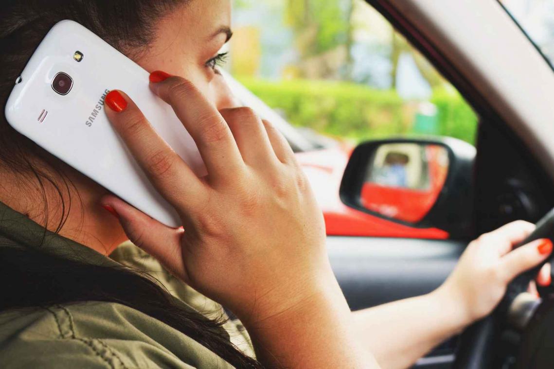 Een jonge bestuurder op de vijf gebruikt smartphone achter het stuur