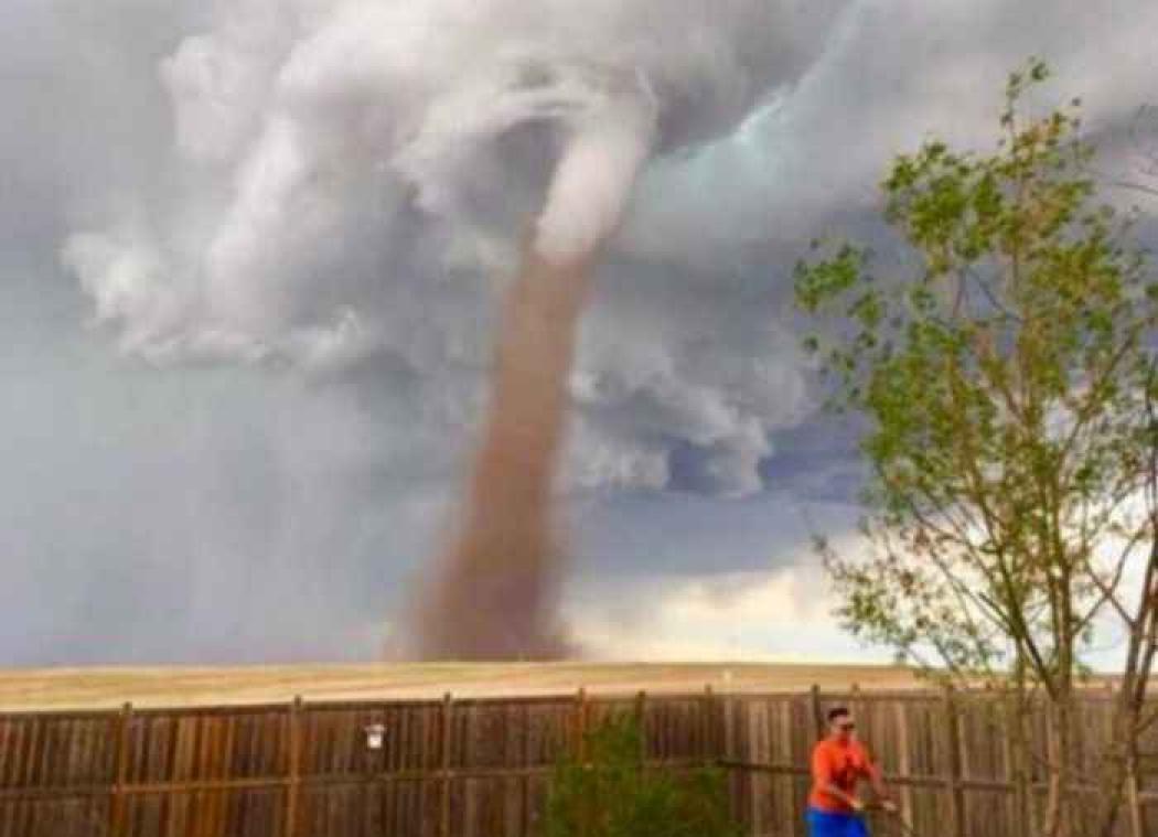 Canadees maait gras terwijl tornado achter hem woedt