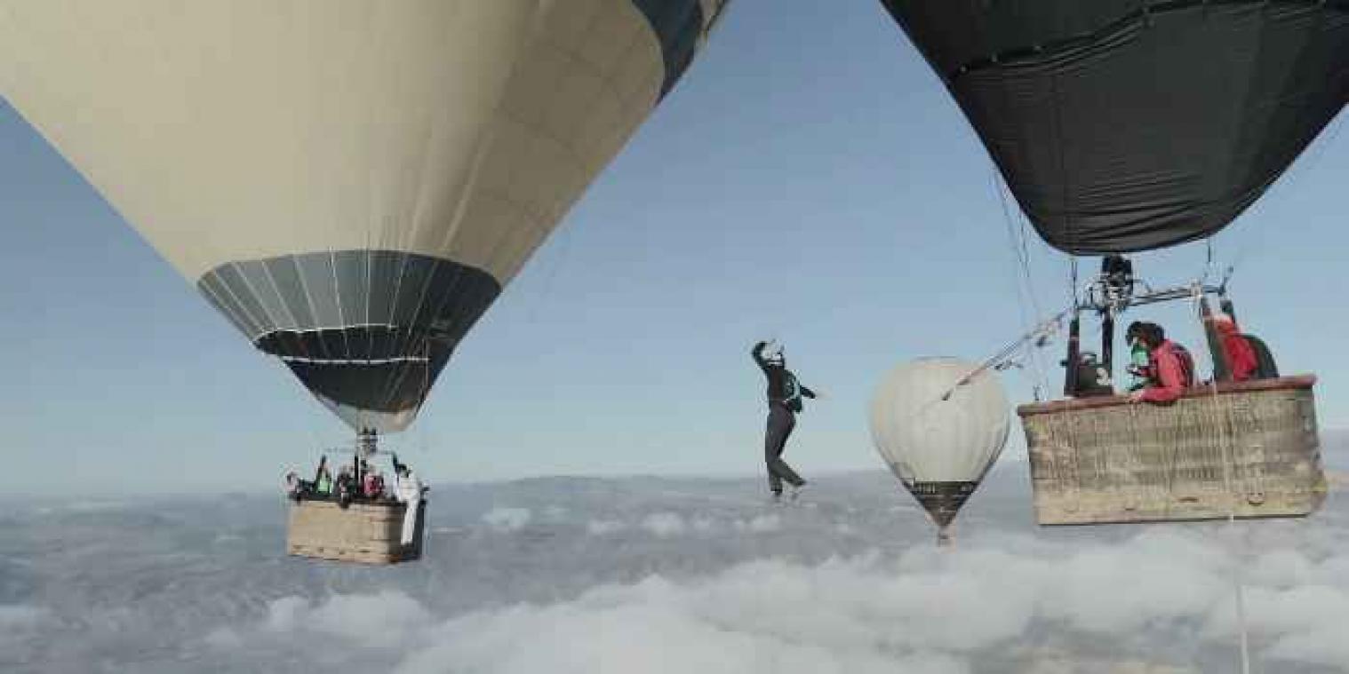 Waaghalzen wandelen op touw tussen luchtballonnen enkele kilometers boven de grond