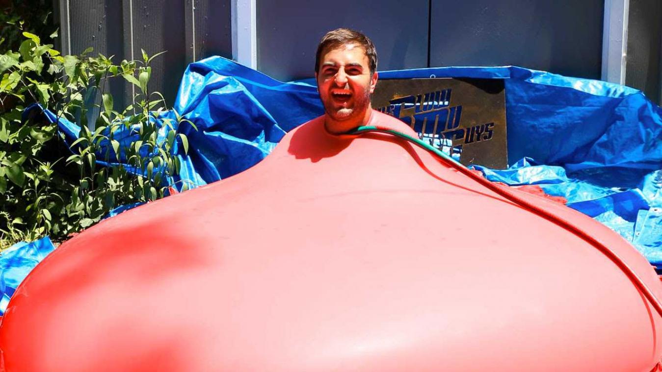 Man kruipt in grote waterballon en laat die vollopen tot die explodeert
