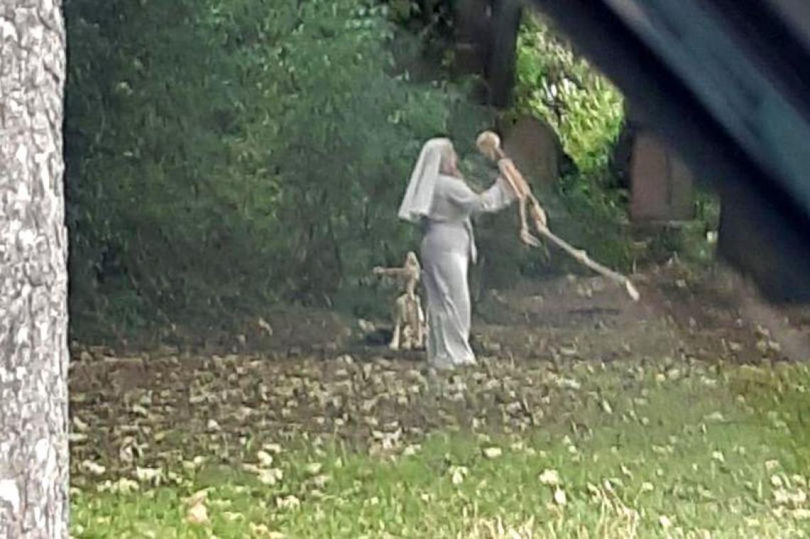 Macaber zicht: vrouw verkleed als non danst met skeletten op oud kerkhof (foto’s)