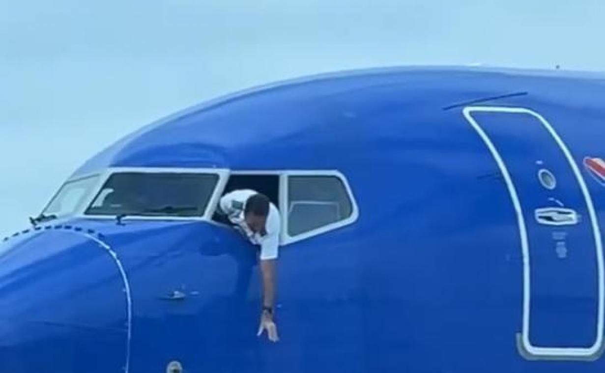 Piloot hangt uit venster van de cockpit om gsm van passagier te vangen (video)