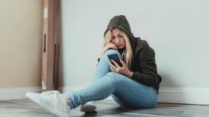 woman-sits-on-the-floor-and-looks-at-her-cellphone